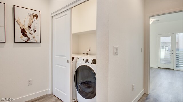 clothes washing area with light hardwood / wood-style floors and washer and clothes dryer