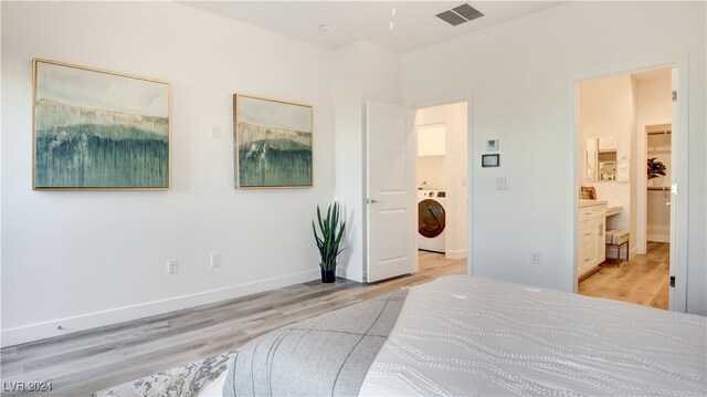 bedroom with ensuite bath, light wood-type flooring, and washer / dryer