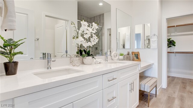 bathroom with walk in shower, vanity, and hardwood / wood-style flooring