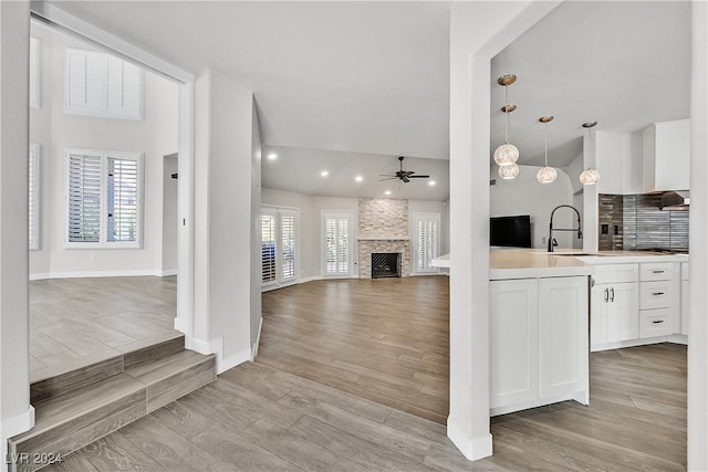 kitchen with light wood-type flooring, ceiling fan, sink, pendant lighting, and white cabinetry