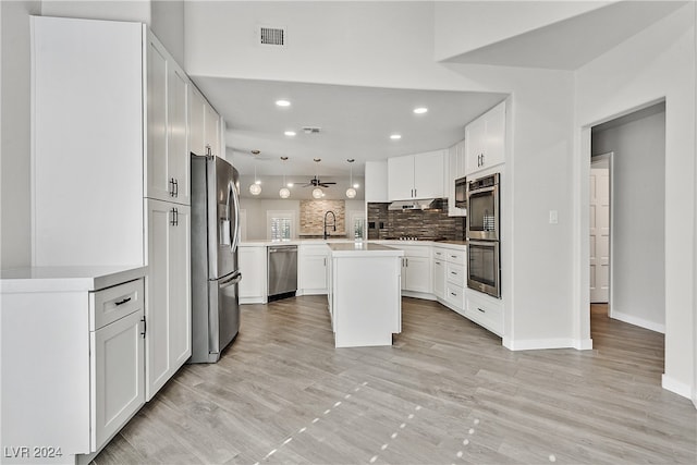 kitchen featuring appliances with stainless steel finishes, a center island, decorative light fixtures, and white cabinetry