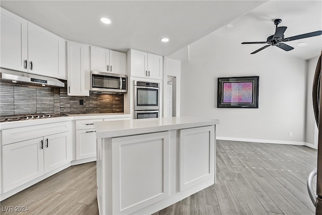 kitchen featuring a center island, white cabinets, decorative backsplash, light wood-type flooring, and stainless steel appliances