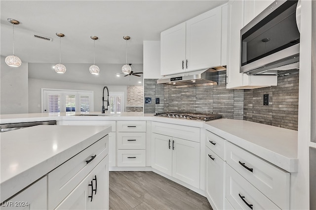 kitchen featuring white cabinetry, ceiling fan, stainless steel appliances, decorative light fixtures, and decorative backsplash