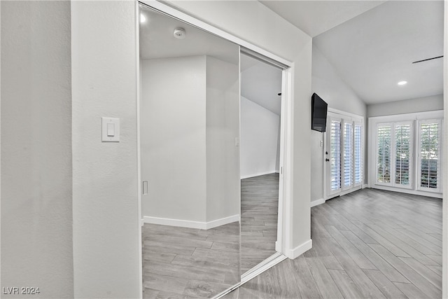 corridor featuring light wood-type flooring and lofted ceiling