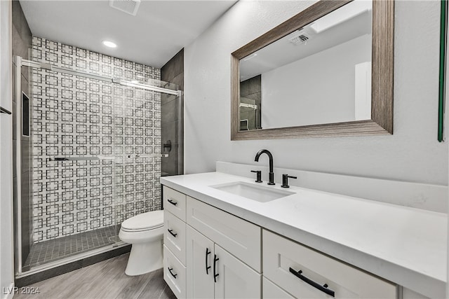 bathroom with an enclosed shower, vanity, tile walls, hardwood / wood-style floors, and toilet