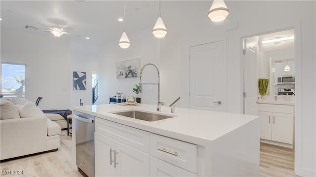 kitchen featuring stainless steel appliances, a kitchen island with sink, pendant lighting, light hardwood / wood-style floors, and white cabinetry