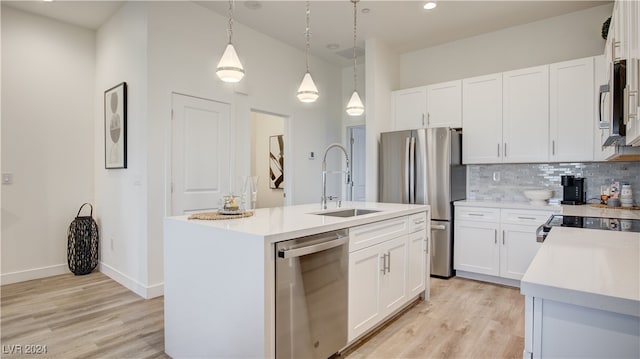 kitchen featuring pendant lighting, stainless steel appliances, a kitchen island with sink, and sink