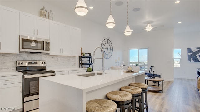 kitchen with a kitchen island with sink, sink, light hardwood / wood-style flooring, appliances with stainless steel finishes, and white cabinetry