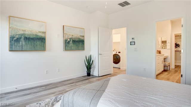 bedroom with connected bathroom, washer / clothes dryer, and light hardwood / wood-style flooring