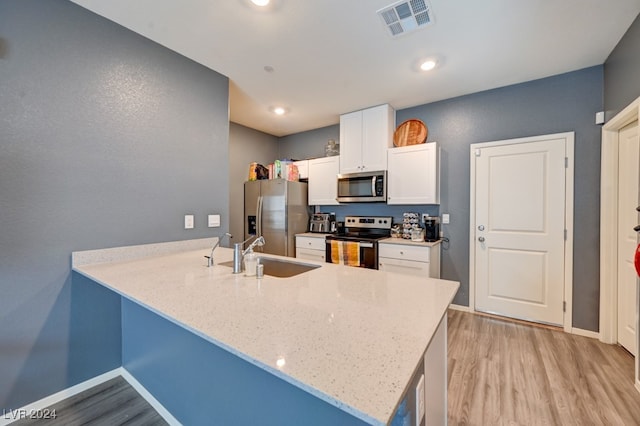 kitchen featuring kitchen peninsula, stainless steel appliances, sink, light hardwood / wood-style flooring, and white cabinetry