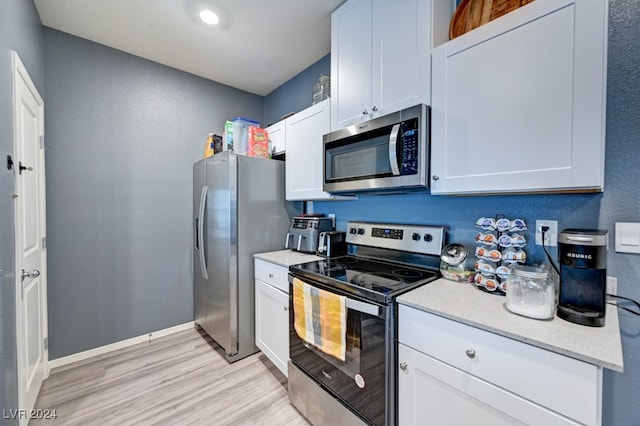 kitchen with white cabinetry, stainless steel appliances, and light hardwood / wood-style flooring