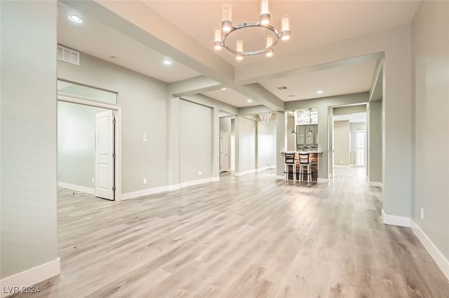 unfurnished living room featuring a chandelier and light hardwood / wood-style floors