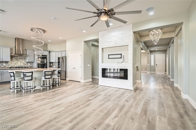 kitchen featuring wall chimney exhaust hood, stainless steel refrigerator with ice dispenser, gray cabinets, a breakfast bar, and a kitchen island