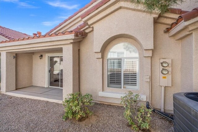 property entrance featuring a tiled roof, cooling unit, and stucco siding