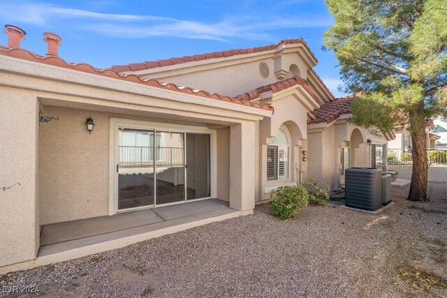 rear view of property featuring cooling unit, a tiled roof, and stucco siding