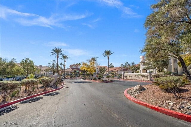 view of street featuring curbs, a gated entry, and a residential view