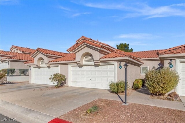 mediterranean / spanish-style house featuring a tile roof, driveway, an attached garage, and stucco siding