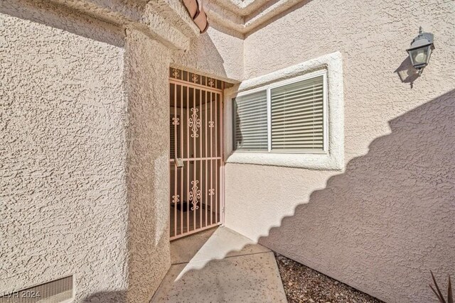 view of exterior entry with visible vents and stucco siding