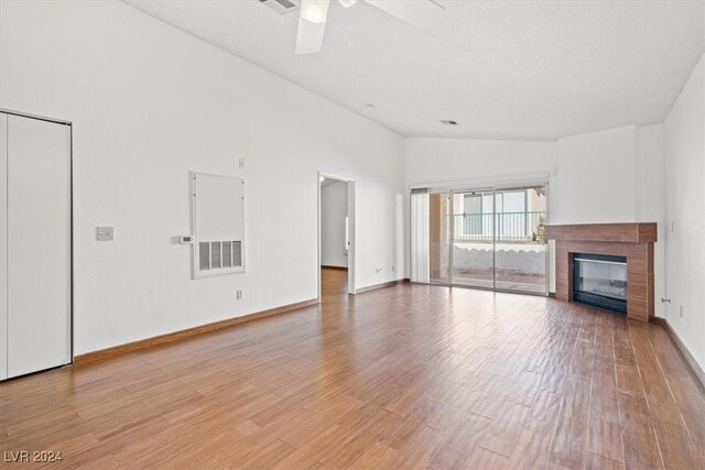 unfurnished living room with a glass covered fireplace, visible vents, light wood-style flooring, and baseboards