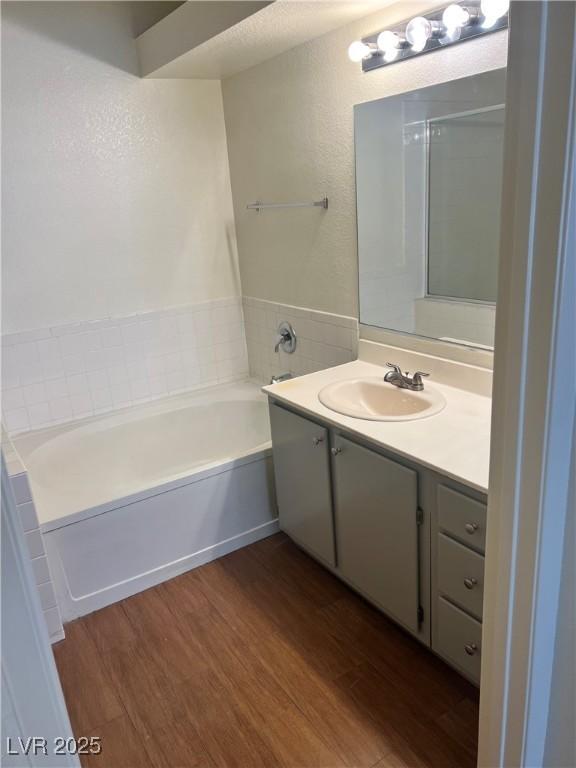 bathroom featuring a garden tub, wood finished floors, and vanity