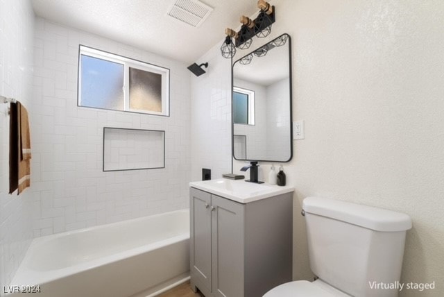 full bathroom featuring tiled shower / bath, vanity, a healthy amount of sunlight, and toilet