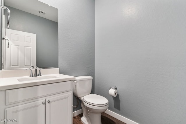 bathroom with hardwood / wood-style floors, vanity, and toilet