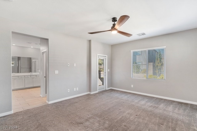 unfurnished bedroom featuring ceiling fan, light colored carpet, ensuite bathroom, and access to outside