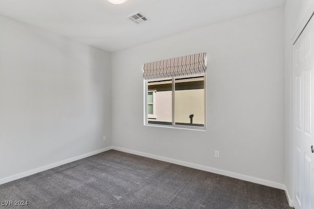 unfurnished room with dark colored carpet