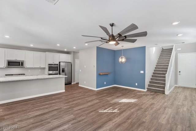 kitchen with dark wood-type flooring, ceiling fan, light stone countertops, appliances with stainless steel finishes, and white cabinetry