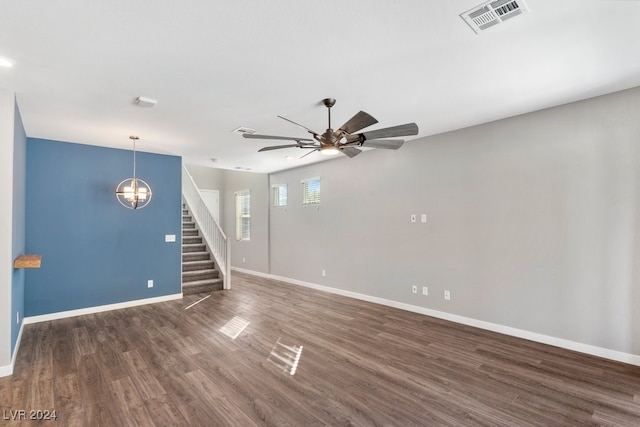 spare room featuring ceiling fan with notable chandelier and dark wood-type flooring