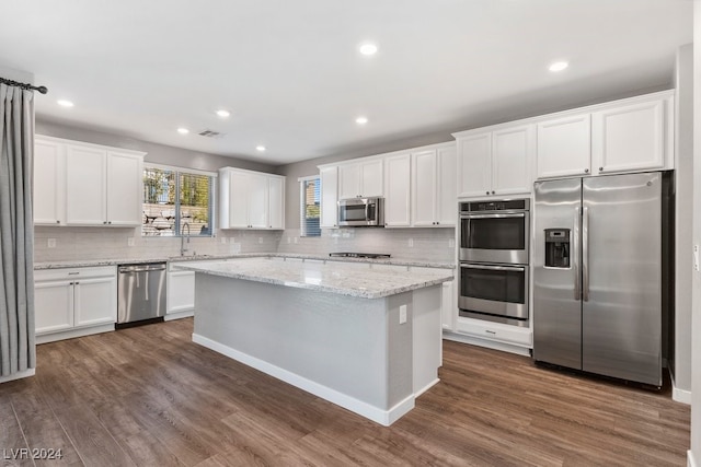 kitchen with stainless steel appliances, a kitchen island, dark hardwood / wood-style flooring, decorative backsplash, and white cabinets