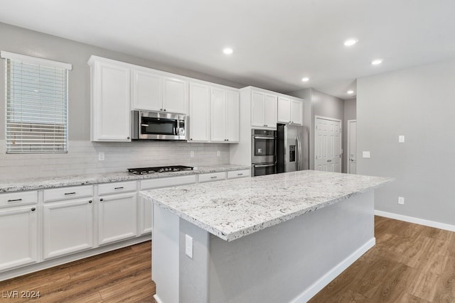 kitchen with a center island, dark wood-type flooring, decorative backsplash, appliances with stainless steel finishes, and white cabinetry