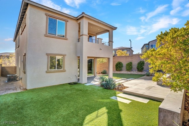 back of property with a lawn, central AC unit, a balcony, and a patio