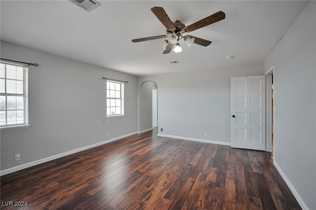 unfurnished room with ceiling fan, plenty of natural light, and dark wood-type flooring