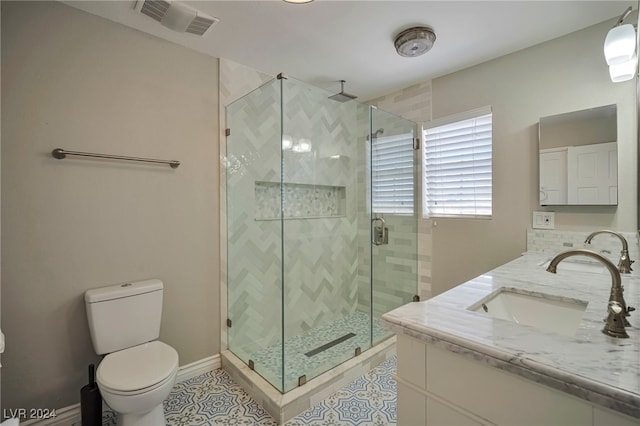 bathroom with tile patterned flooring, vanity, toilet, and walk in shower