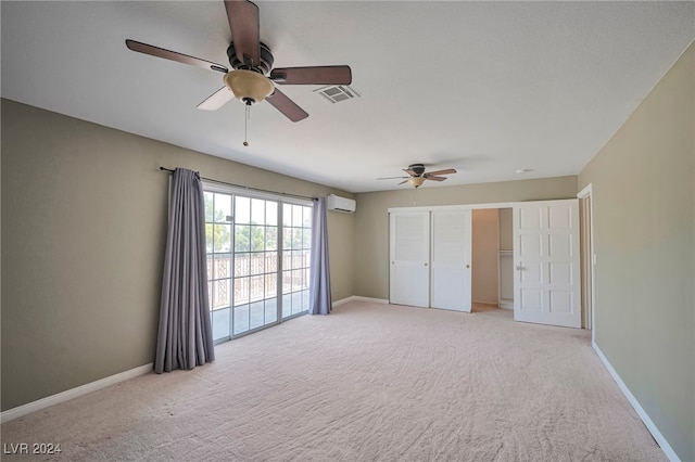 unfurnished bedroom featuring a wall mounted AC, light carpet, access to exterior, and ceiling fan