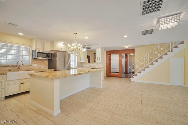 kitchen featuring appliances with stainless steel finishes, hanging light fixtures, a healthy amount of sunlight, and sink