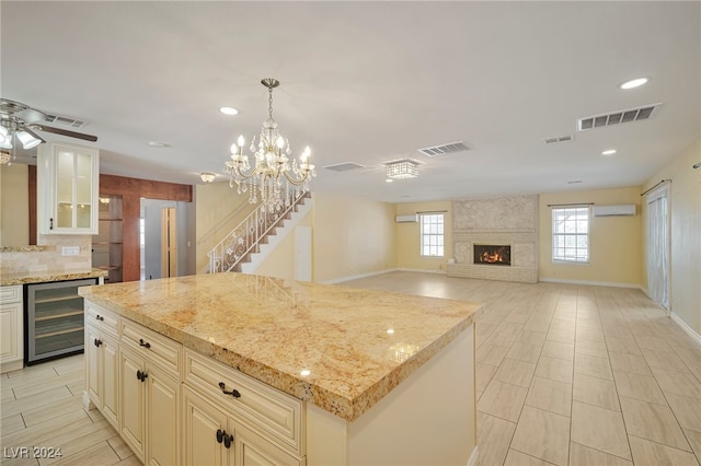 kitchen with a large fireplace, a kitchen island, light stone countertops, and beverage cooler