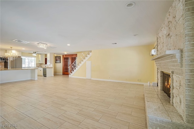 unfurnished living room featuring ceiling fan with notable chandelier and a fireplace