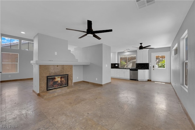 unfurnished living room with ceiling fan and a tiled fireplace