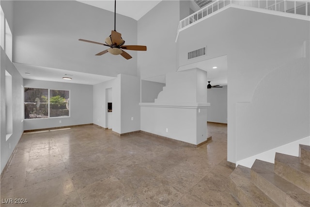 unfurnished living room with ceiling fan and a towering ceiling