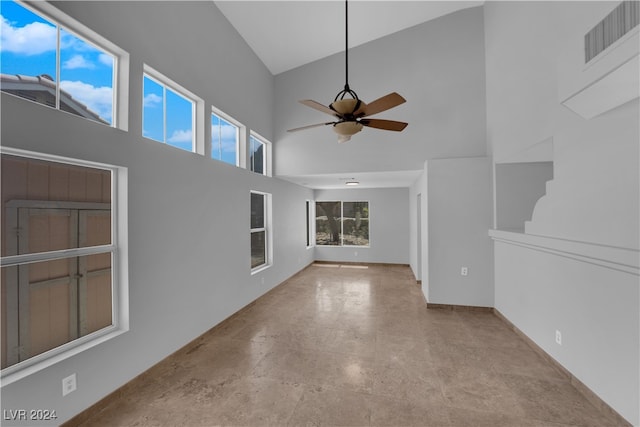 unfurnished living room with ceiling fan and high vaulted ceiling