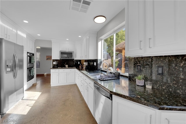 kitchen featuring dark stone countertops, white cabinetry, sink, and appliances with stainless steel finishes