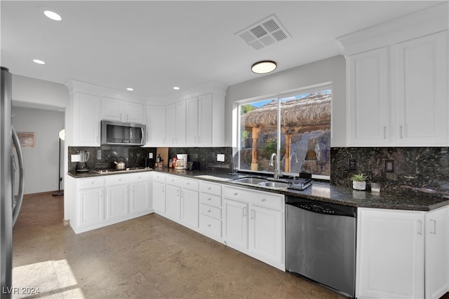 kitchen with tasteful backsplash, stainless steel appliances, sink, dark stone countertops, and white cabinetry