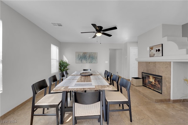 dining space with ceiling fan and a tiled fireplace