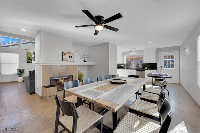 dining room with a tile fireplace and ceiling fan