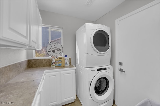 laundry room featuring stacked washer / drying machine and cabinets