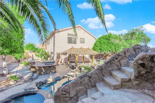 rear view of property with an outdoor kitchen and a patio