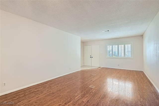 unfurnished room featuring hardwood / wood-style flooring and a textured ceiling