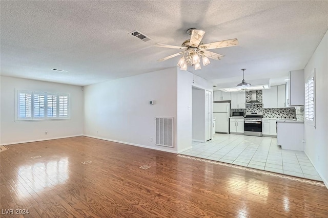 unfurnished living room with ceiling fan, light hardwood / wood-style flooring, and a textured ceiling